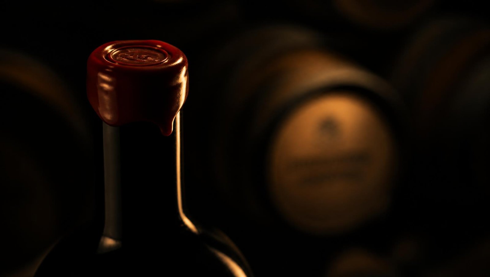 Cuello de botella de vino con lacre rojo en una bodega en penumbra